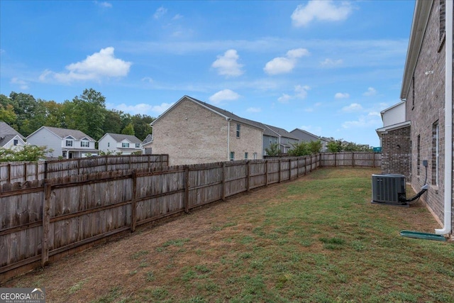 view of yard featuring central AC unit, a residential view, and a fenced backyard