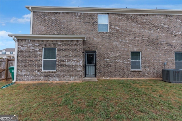 back of property featuring cooling unit, a lawn, and brick siding