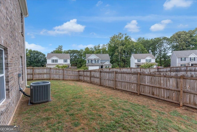 view of yard with central air condition unit, fence, and a residential view