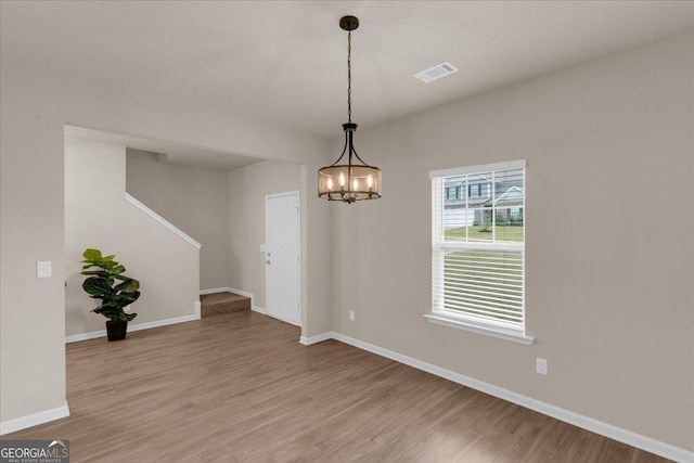 spare room featuring visible vents, stairs, light wood-type flooring, and baseboards