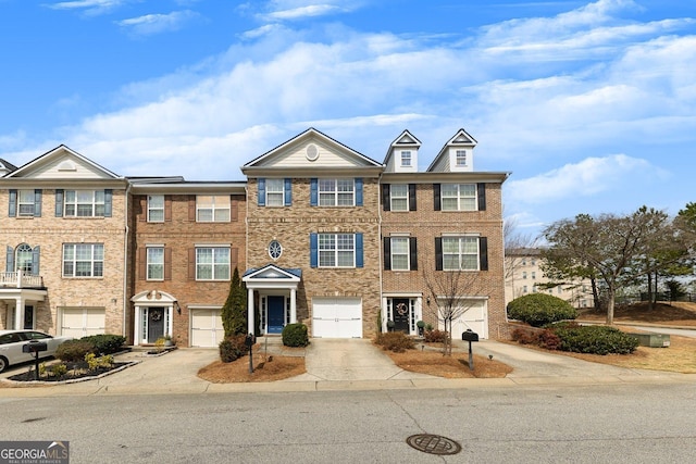 view of property with an attached garage, brick siding, and driveway