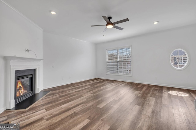 unfurnished living room with baseboards, recessed lighting, wood finished floors, a glass covered fireplace, and a ceiling fan