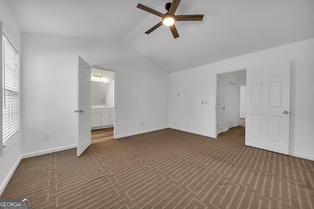 unfurnished bedroom with ceiling fan, vaulted ceiling, baseboards, and connected bathroom