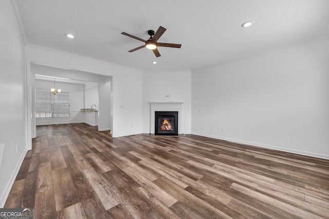 unfurnished living room with a fireplace with flush hearth, dark wood finished floors, a ceiling fan, and ornamental molding