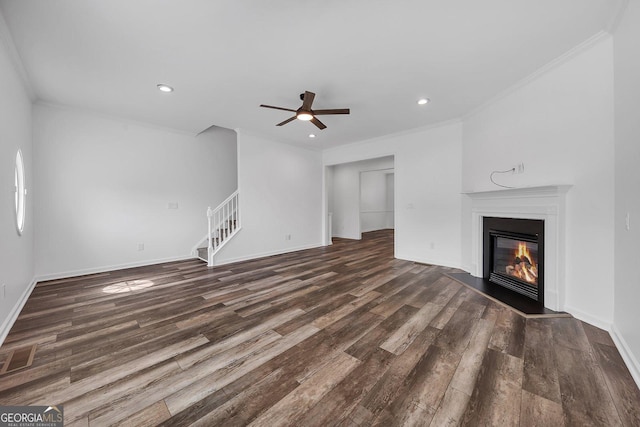 unfurnished living room featuring crown molding, stairs, wood finished floors, a glass covered fireplace, and a ceiling fan