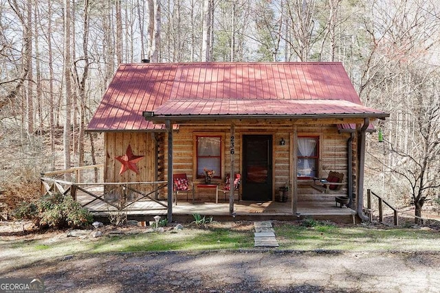 chalet / cabin featuring log siding, metal roof, and covered porch