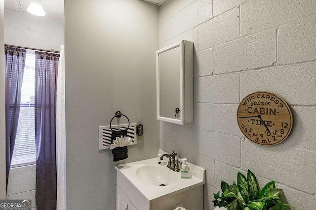 bathroom featuring vanity and concrete block wall