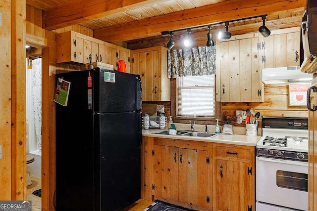 kitchen with white range with gas cooktop, freestanding refrigerator, a sink, light countertops, and under cabinet range hood