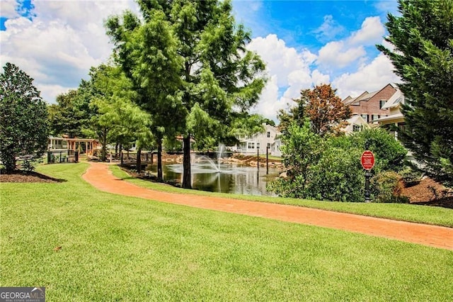 view of property's community with a lawn and a water view