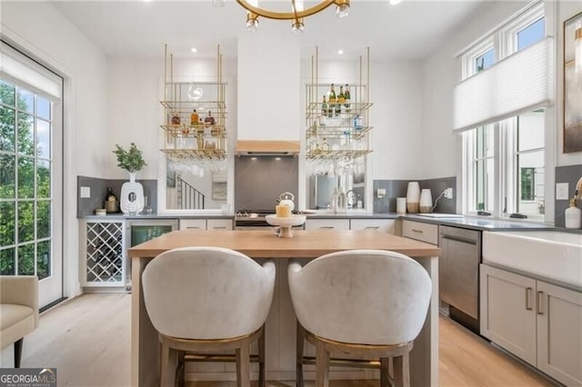 bar featuring light wood finished floors, recessed lighting, a sink, decorative backsplash, and dishwasher