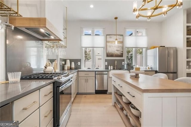 kitchen featuring recessed lighting, light wood-style flooring, appliances with stainless steel finishes, hanging light fixtures, and a sink