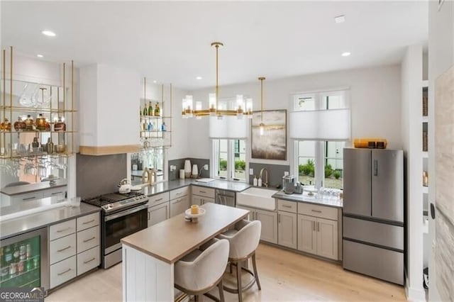 kitchen featuring light wood-type flooring, a sink, wine cooler, appliances with stainless steel finishes, and a chandelier