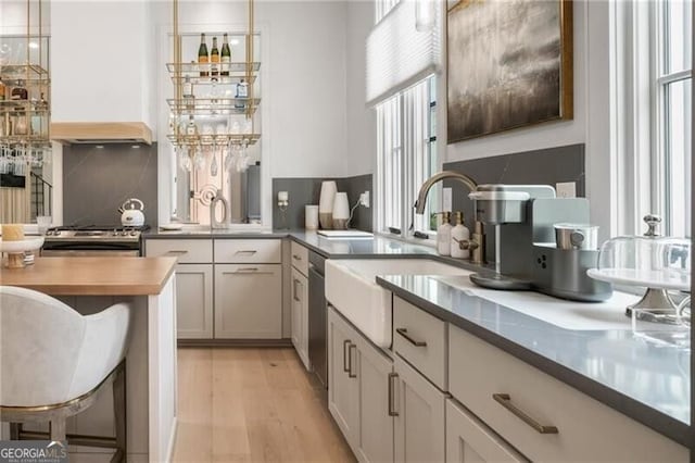 kitchen featuring light wood-style flooring, a sink, stainless steel appliances, a kitchen breakfast bar, and backsplash