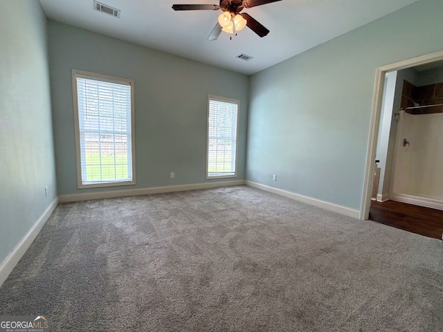 empty room with visible vents, carpet floors, baseboards, and ceiling fan