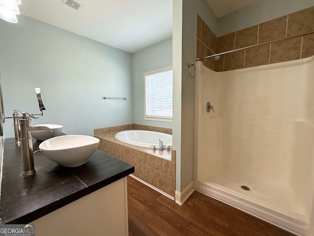 bathroom featuring visible vents, a garden tub, walk in shower, and wood finished floors