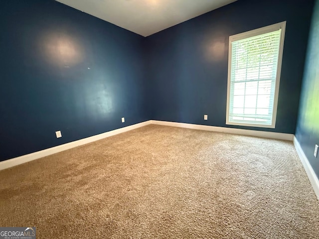 carpeted spare room featuring baseboards