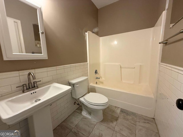 bathroom featuring tile walls, toilet, and a wainscoted wall