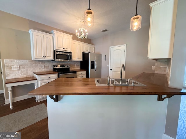 kitchen with visible vents, decorative backsplash, a peninsula, stainless steel appliances, and a sink