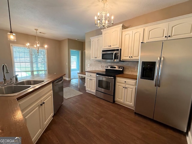 kitchen featuring a notable chandelier, a sink, dark wood finished floors, appliances with stainless steel finishes, and decorative backsplash