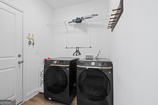 clothes washing area featuring laundry area, wood finished floors, separate washer and dryer, and baseboards