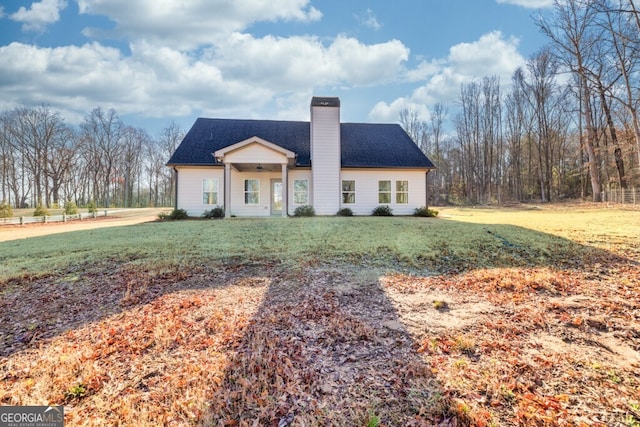 view of front of house featuring a front yard, roof with shingles, and a chimney