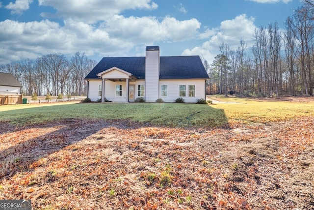 view of front of property featuring a front lawn, a chimney, and a shingled roof