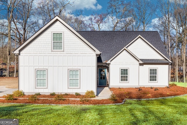 modern inspired farmhouse featuring roof with shingles, board and batten siding, and a front lawn