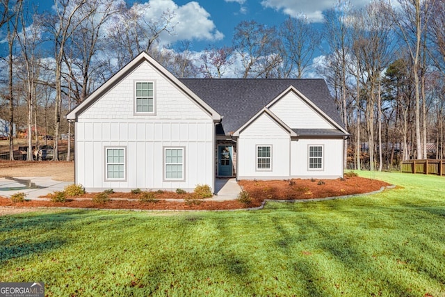 modern farmhouse style home featuring a front lawn, fence, board and batten siding, and a shingled roof