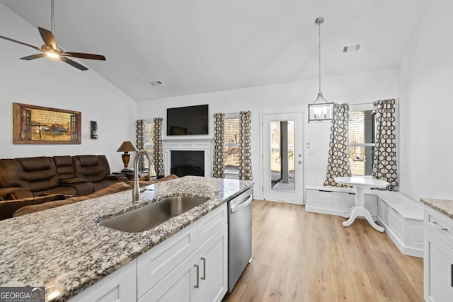 kitchen with lofted ceiling, a sink, open floor plan, dishwasher, and light wood-type flooring