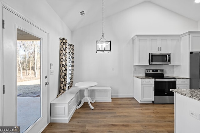 kitchen with visible vents, lofted ceiling, appliances with stainless steel finishes, wood finished floors, and hanging light fixtures