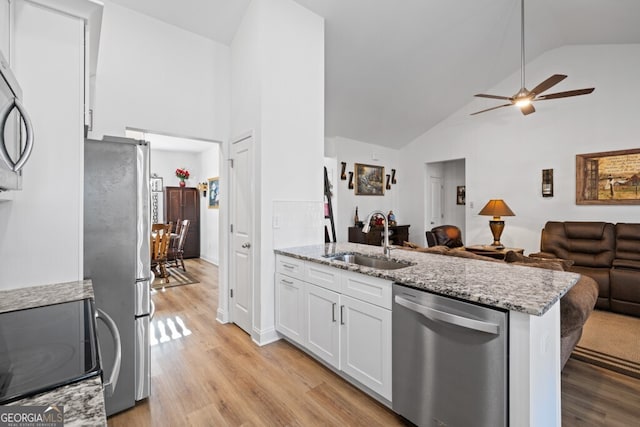 kitchen featuring light wood-type flooring, a sink, open floor plan, white cabinetry, and stainless steel appliances