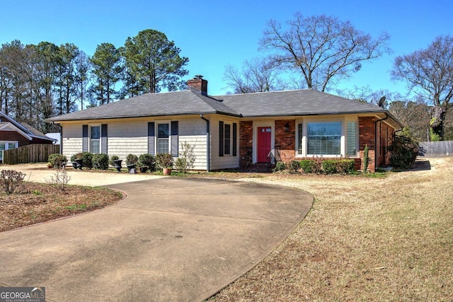 single story home featuring a front yard, concrete driveway, fence, and a chimney