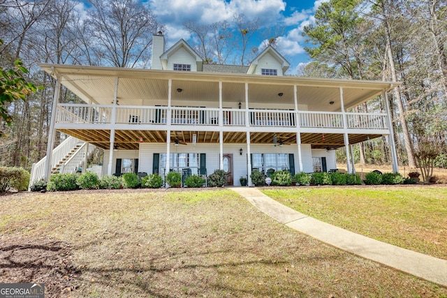 rear view of house featuring stairway, a lawn, ceiling fan, and a chimney