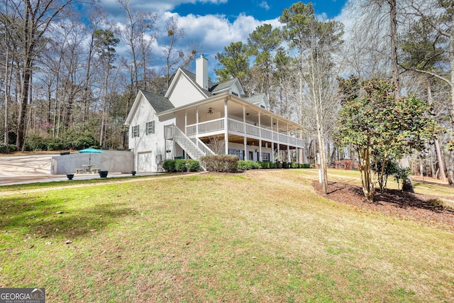 back of house with a chimney, stairway, a ceiling fan, and a yard