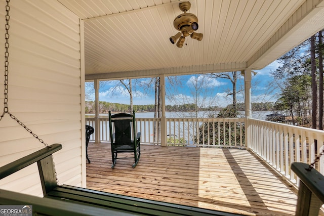 deck with a ceiling fan and a water view