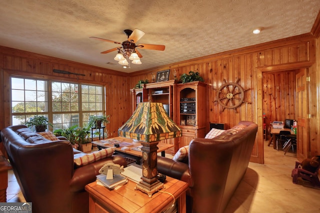 living area featuring wood walls, a textured ceiling, a ceiling fan, and ornamental molding