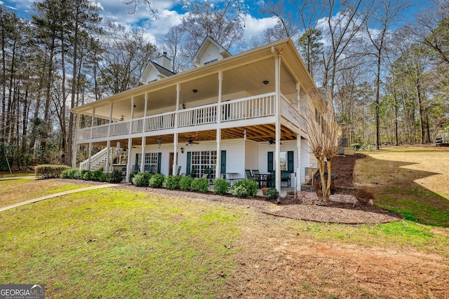 back of property featuring stairs, a lawn, ceiling fan, and a chimney