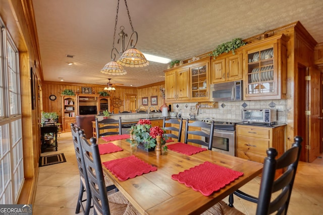 dining room featuring light tile patterned floors, a toaster, ornamental molding, ceiling fan, and a textured ceiling