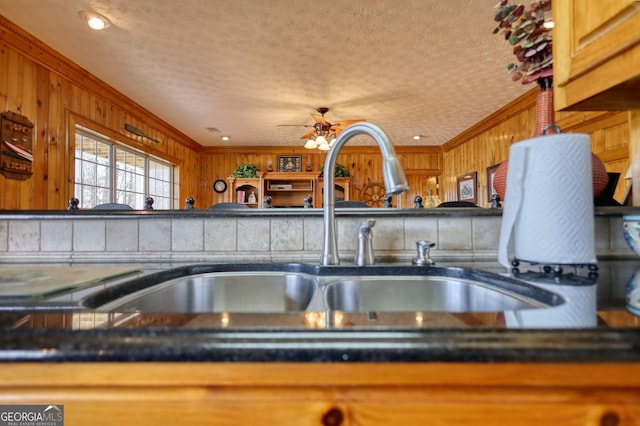 kitchen featuring dark countertops, crown molding, ceiling fan, a textured ceiling, and a sink