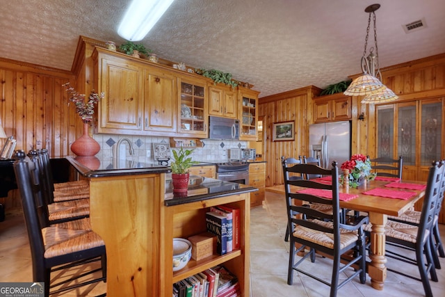 kitchen featuring dark countertops, visible vents, appliances with stainless steel finishes, and wood walls