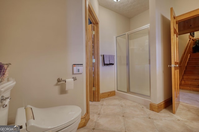 full bathroom featuring tile patterned floors, toilet, a shower stall, and a textured ceiling