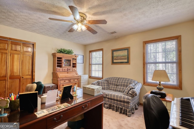 office with visible vents, ceiling fan, a textured ceiling, and carpet