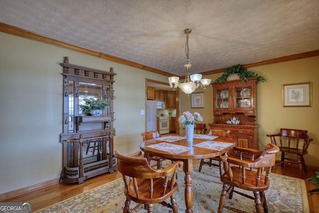 dining area featuring a textured ceiling, light wood-type flooring, baseboards, and ornamental molding