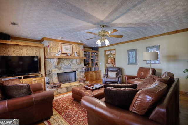 living area with visible vents, a textured ceiling, ornamental molding, and a fireplace