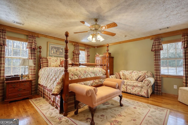 bedroom with visible vents, a textured ceiling, and wood finished floors