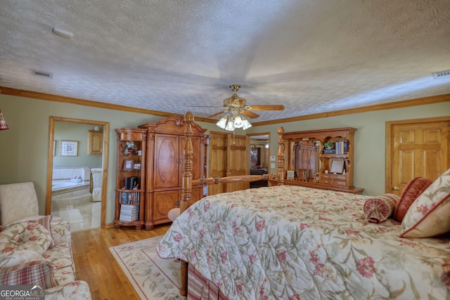 bedroom with visible vents, light wood-style floors, ornamental molding, and a textured ceiling