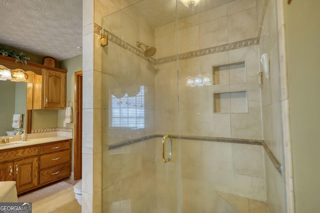 bathroom with a textured ceiling, a stall shower, vanity, and toilet