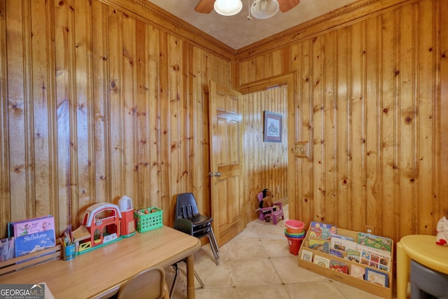 recreation room with tile patterned flooring, wooden walls, and a ceiling fan