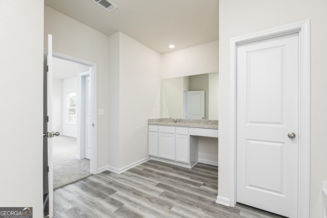 bathroom featuring visible vents, vanity, baseboards, and wood finished floors