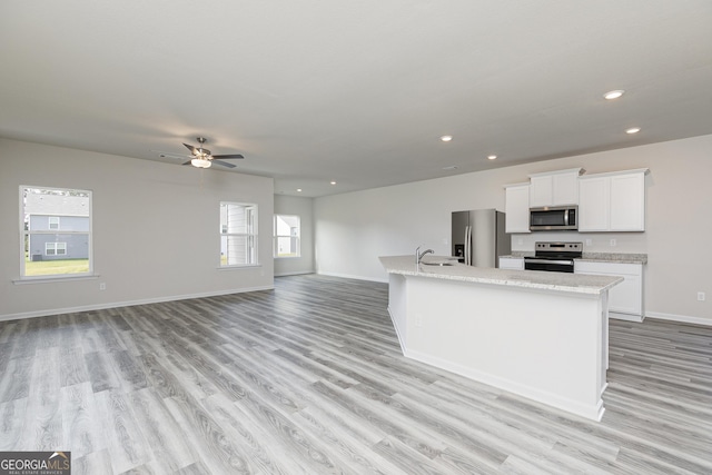 kitchen featuring light wood finished floors, recessed lighting, a sink, white cabinets, and appliances with stainless steel finishes